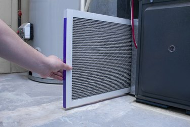 Una persona que cambia un filtro de aire en un horno de alta eficiencia