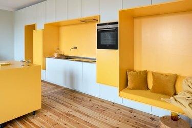 Piani di lavoro giallo cromo con armadi bianchi in una cucina moderna e minimalista di ispirazione scandinava