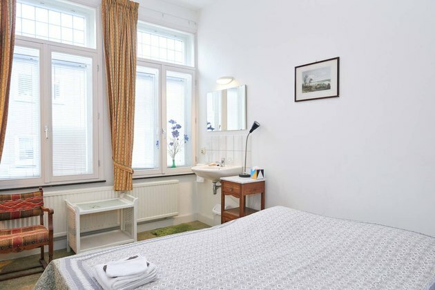 quarto com cama branca e janelas grandes em Maastricht