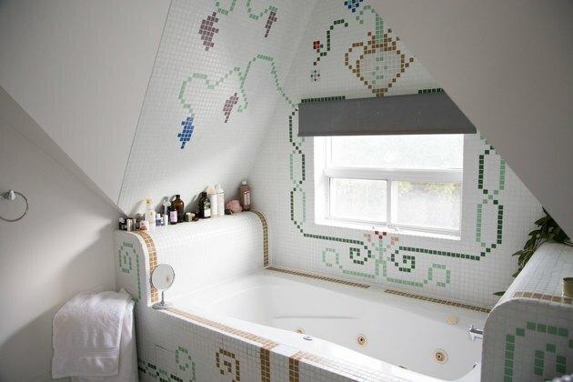 banheira de hidromassagem com azulejos decorativos em torno dela, produtos de banho na borda da banheira