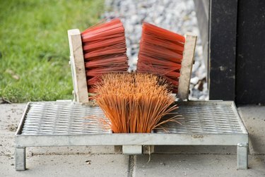 Moderni saappaiden kaavin, jossa on oranssit harjakset kiinnitetty hopeanväriseen metallilevyyn.