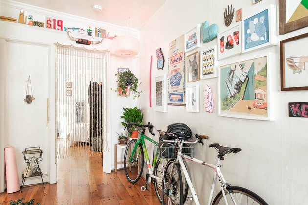 Ideias para iluminação de corredores no corredor de um apartamento com obras de arte e bicicletas apoiadas nelas