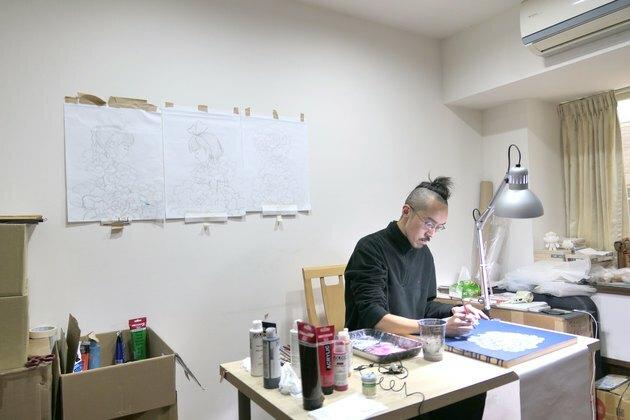 Menininkas Martinas Hsu prie savo stalo savo laikinojoje studijoje Taivane