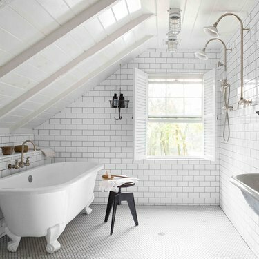 banheiro branco no sótão com banheira vitoriana e backsplash de azulejos de metrô