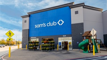 Uma foto do exterior do Sam's Club com uma parede azul e um logotipo branco.