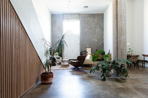 kaasaegne istumisnurk betoonpõrandate, puitpaneelide seinte ja rohelusega