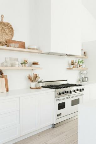 Grande cozinha branca com decoração boho e gama profissional com forno duplo