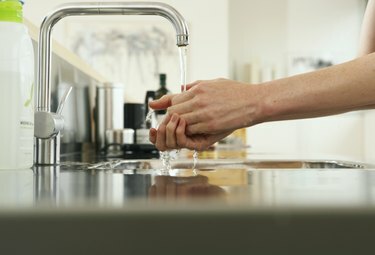 Kvinde, der vasker hænder ved køkkenvasken, udsigt langs skranken, tæt på