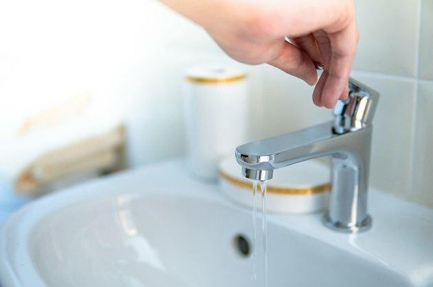 Macho mano apertura agua grifo o grifo en el baño. Ahorre agua en casa o conceptos de conservación de agua