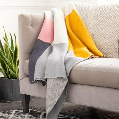 sofá com manta colorblock e planta próxima