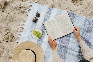 toalha de praia e livro na areia