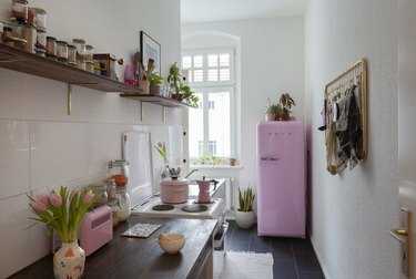 virtuve ar brūniem skapjiem un rozā sadzīves tehniku