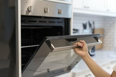 Le mani aprono il forno in cucina