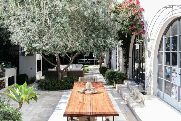 Mesa de madeira do pátio com plantas e um edifício branco de estilo mediterrâneo com janelas em arco