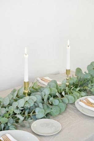 um corredor de mesa feito de ramos de eucalipto cravejados com velas para a peça central de Natal