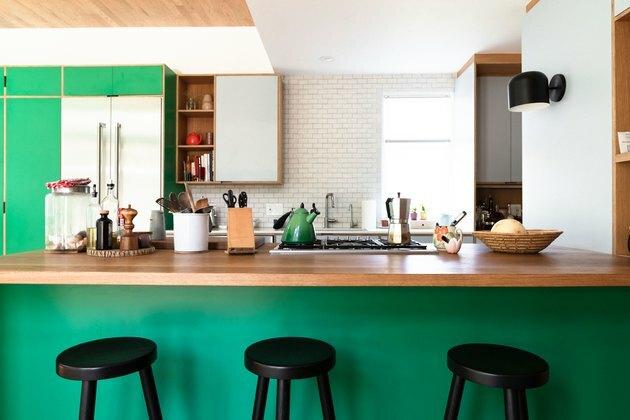 cucina verde con ripiani in blocco da macellaio e sgabelli neri