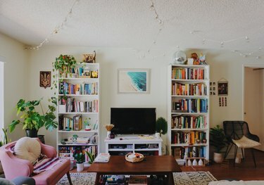 woonkamer met roze stoel, twee boekenplanken en televisie