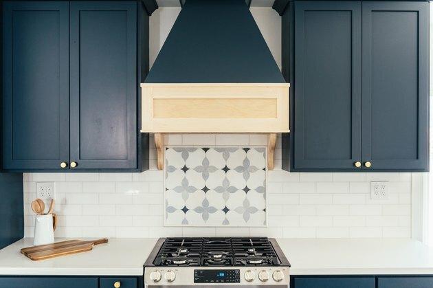 Cozinha com armários azuis, backsplash de ladrilhos brancos e ladrilhos padronizados atrás do fogão