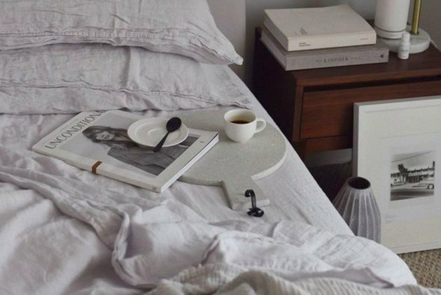 Cama desfeita com lençóis brancos e uma xícara de café