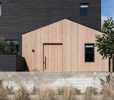 Esterno moderno della casa con rivestimenti in legno nero e naturale, finestre nere.