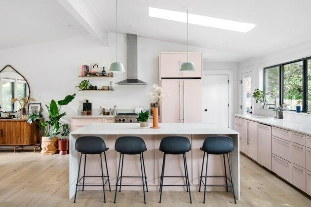ilha de cozinha moderna em espaço rosa e branco com bancos pretos