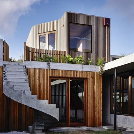 Exterior contemporâneo da casa com revestimento de madeira e escada em caracol