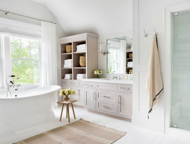 Kúpeľňa Shabby Chic v kúpeľni s veľkou vaňou, vstavanými skrinkami a policami, uterákmi, stoličkou, kvetinami, kobercami.