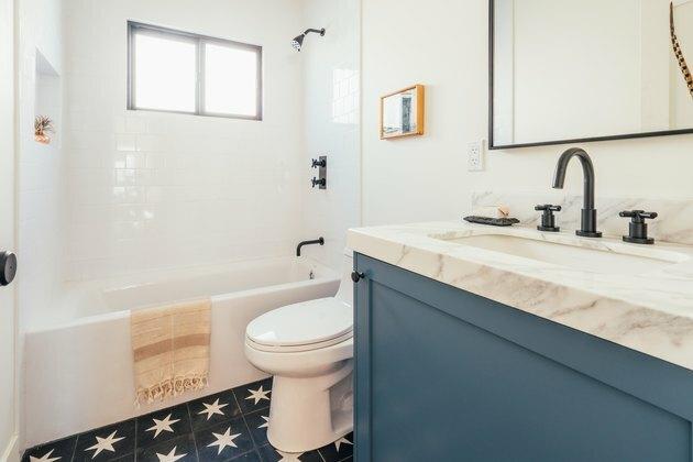 Banheiro com piso de azulejo estrela azul e branco e bancada em mármore na pia pintada de azul