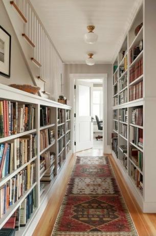 Ideias de pontos focais para corredores em corredores creme com estantes de livros ao longo da parede