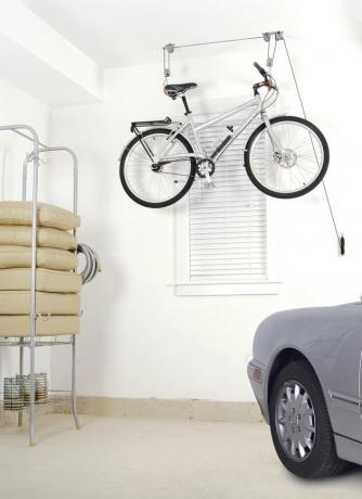 armazenamento de bicicletas pendurado em um sistema de polia em uma garagem com um carro