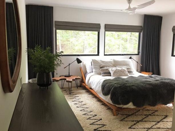 نوافذ سوداء في غرفة النوم بها سجادة ذات نمط هندسي ، وسرير منصة ، وطاولة سرير جذابة