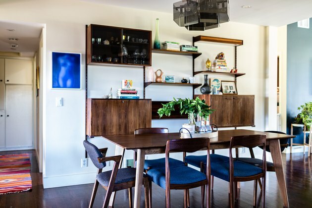 ideia de decoração de parede de sala de jantar com móveis de madeira e cadeiras almofadadas azuis e um aparador de madeira
