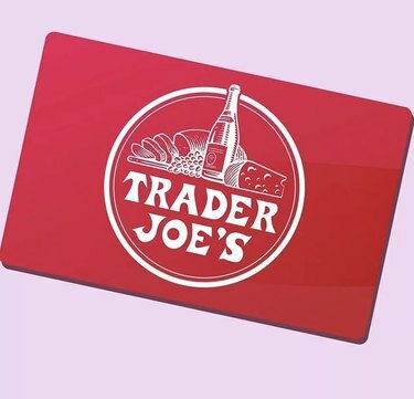 Crvena darovna kartica Trader Joea s logotipom na blijedoružičastoj pozadini.