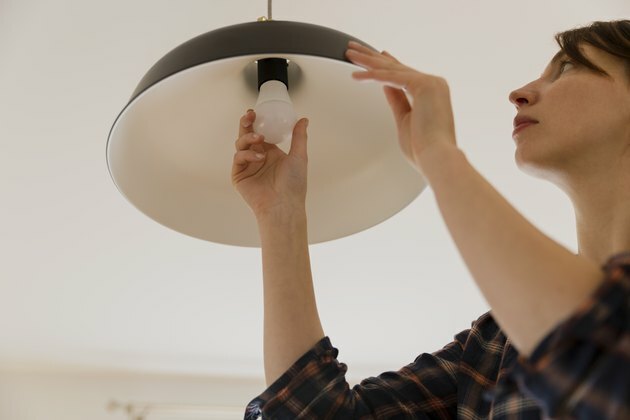 Sieviete mājās aizstāj spuldzi. Enerģijas taupīšanas LED lampa mainās