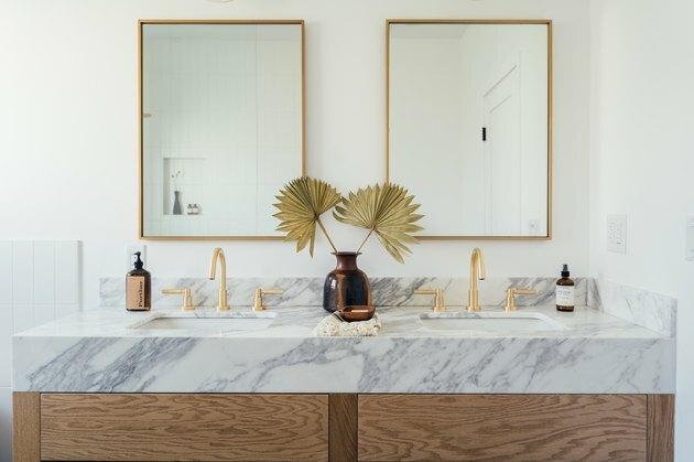 toalett i bad med marmorbenk, doble vasker med gullarmaturer, to rektangulære speil med gullbekledning