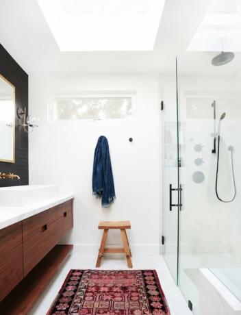 فكرة ستارة الحمام في الحمام الأبيض في الغالب مع الغرور الخشبي ، والجدار الأسود خلف المرآة ، ونافذة صغيرة وكوة