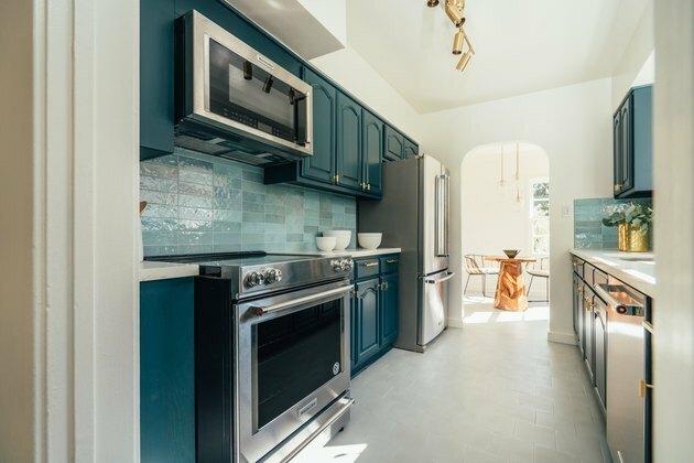 Armários azul-petróleo, fogão de indução, backsplash em azulejo azul-petróleo claro, microondas.