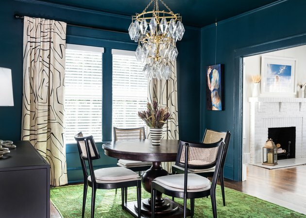 لون طلاء أزرق داكن في غرفة الطعام مع طاولة وعلاجات نافذة بيج