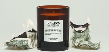 Infliacijos žvakė šalia degančių dolerių banknotų