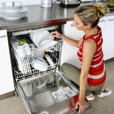 kvinde, der lægger tallerkener i en opvaskemaskine