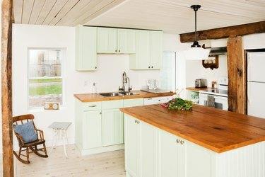 полудървена кухня с дървен таван, борен остров, дървени подове, зелени шкафове и дървен таван