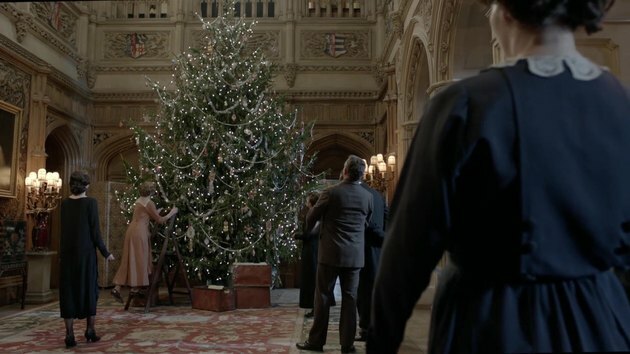 scène uit Downton Abbey met figuren rond een kerstboom