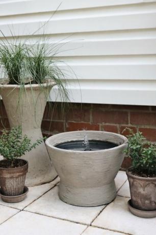 Fontana d'acqua in cemento fai-da-te sul patio con fioriere