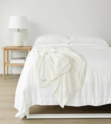 Um quarto branco com uma cama e uma mesa de cabeceira