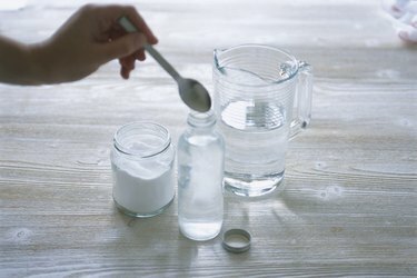 Προσθήκη κονιοποιημένου βόρακα σε μπουκάλι νερό, χρησιμοποιώντας κουτάλι, κοντινό πλάνο