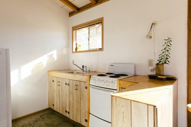 uma cozinha com armários de madeira natural e um fogão elétrico do tamanho de um apartamento