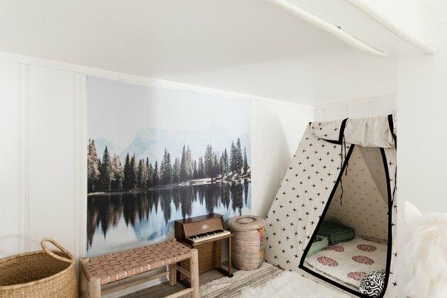 Kinderkamer met tipi, groot canvas met buitenscène en speelgoedpiano.