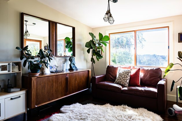 Uma sala de estilo boho com almofadas, aparador de madeira e plantas