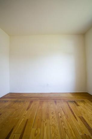 Празна соба са дрвеним подовима и белим зидовима