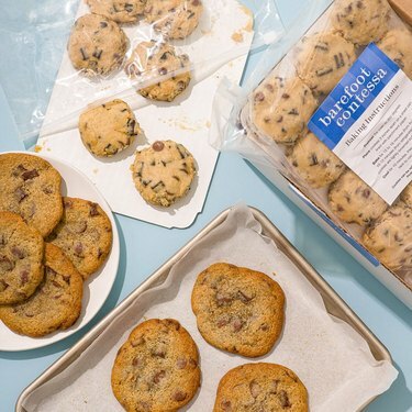 Biscotti al cioccolato su un vassoio e su un piatto bianco con palline di pasta biscotto sullo sfondo.